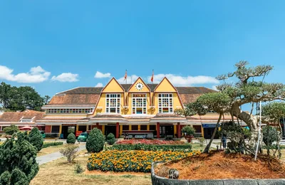 The historic yellow Art Deco facade of Da Lat Railway Station under a blue sky