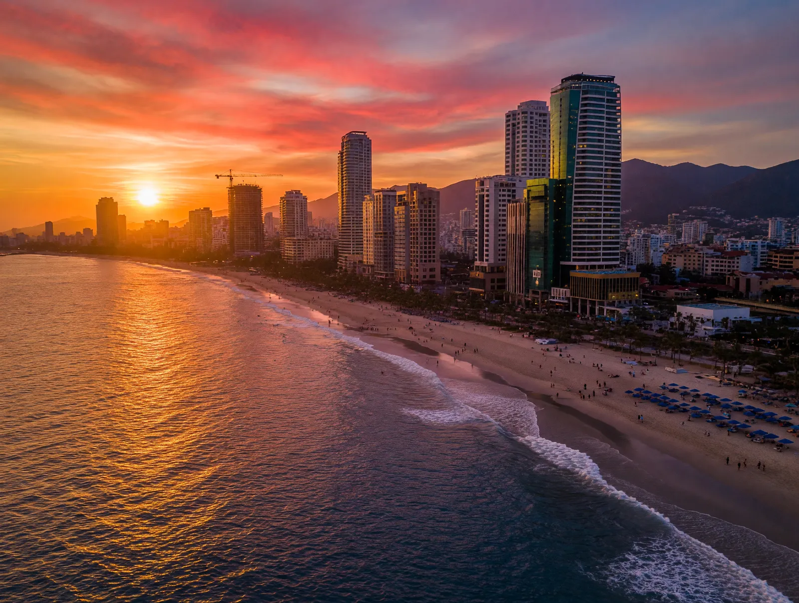 Da Nang skyline at sunset along My Khe Beach with high-rise buildings reflecting on the water