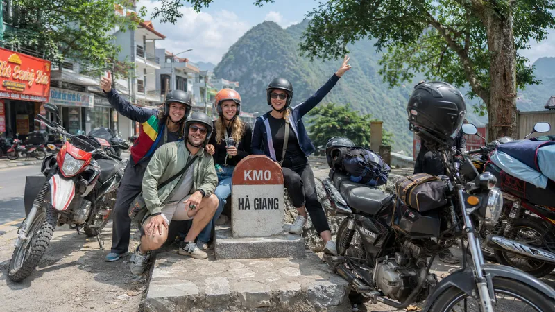 Group of travellers at the KM0 Ha Giang marker ready to start the loop