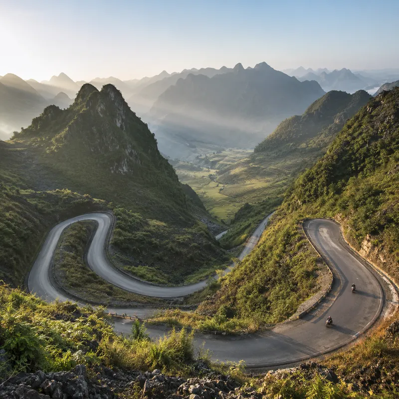 Dramatic switchback road winding down a deep Ha Giang Loop valley at dawn in northern Vietnam