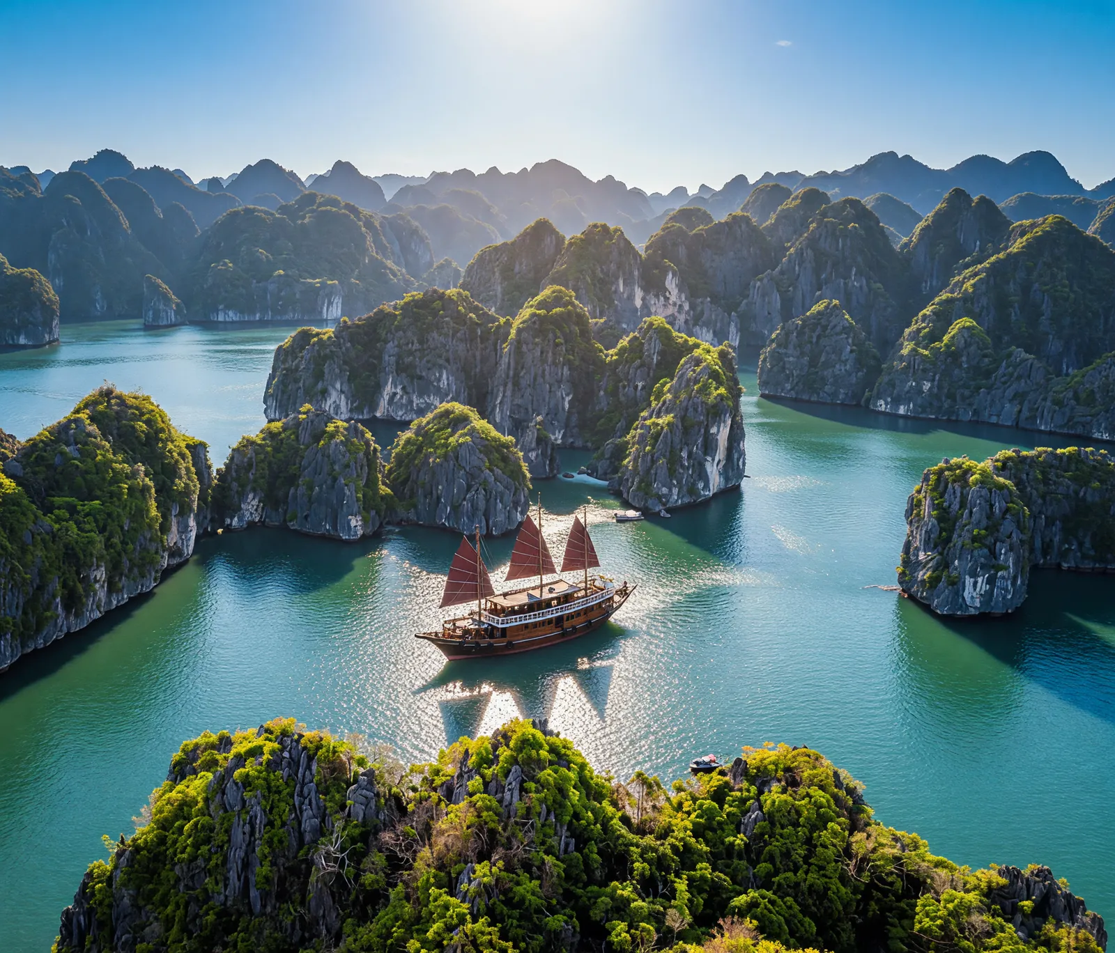 Aerial view of a Vietnamese junk boat sailing through Ha Long Bay limestone islands at golden hour