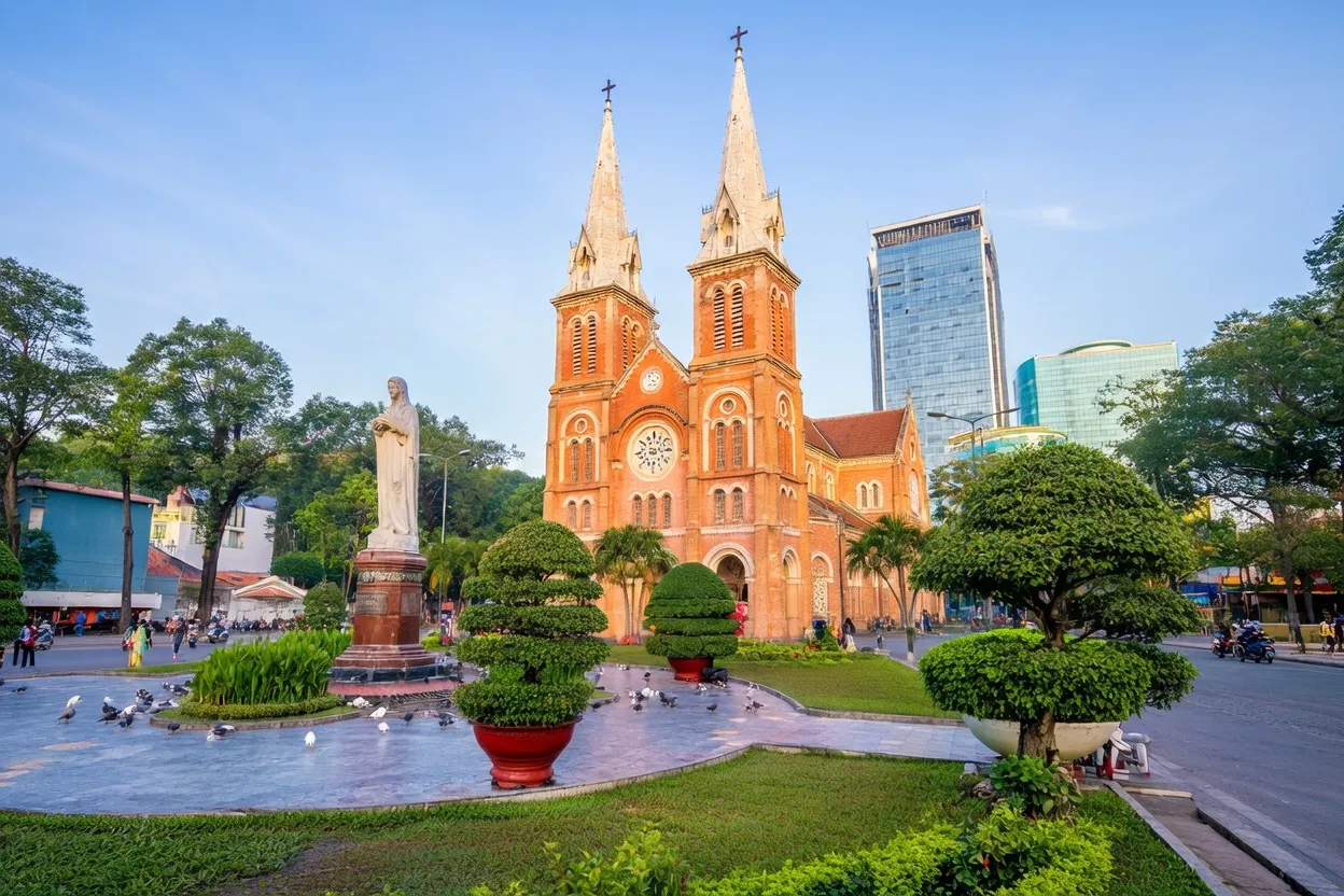 Notre-Dame Cathedral Basilica of Saigon with twin red-brick spires and the Virgin Mary statue in the plaza